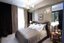 Men's bedroom in shades of gray with a double bed in front of floor-to-ceiling curtains