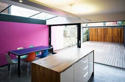 Open living room with free standing kitchen unit in front of a dining area and spacious patio window