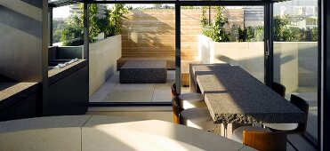 Breakfast bar made of gray stone and bar stools in front of a terrace window and view of a stone block