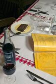 A menu, red wine and dessert on a table in a restaurant
