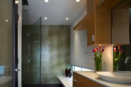 Modernes Bad mit grünen Fliesen an Wand und offener Glastür