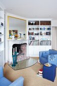 View into a living room with blue furniture, book shelve and fireplace