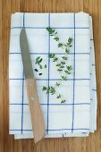 Thyme sprigs and leaves on a tea towel with a knife