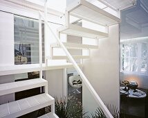 Weisses Treppenhaus mit Durchblick auf modernen Wohnraum mit Kugelsessel