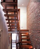 Two flights of stairs next to exposed brickwork wall with spotlights in English house