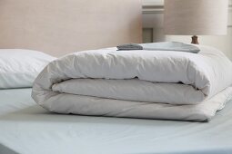 Folded white bedspread on bed