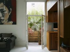 Modern living room with open balcony doors and view of palms in wooden planter