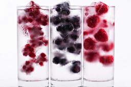 Three glasses of water with various berry ice cubes