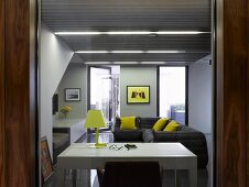 View through open door to white desk and grey sofa