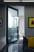 Wohnzimmer mit spiegelndem Boden und offener Tür aus Glas mit Blick in Vorraum
