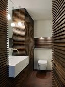 Dark wooden slatted cladding on walls in designer bathroom