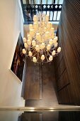 View of retro ceiling light with multiple shades in modern hallway with dark wooden wall