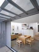 View of dining area with classic chairs and a modern kitchen through open sliding terrace door