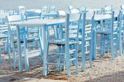 Ferienstimmung; pastellblaue Tische und Stühle einer griechischen Taverne im Sonnenlicht