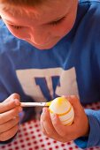 A little boy painting an Easter egg