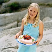 A blonde girl serving a berry tart in the open air