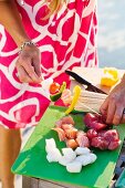 Frau bereitet Spiesse zum Grillen vor