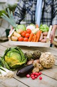 A man holding a crate of fresh vegetables