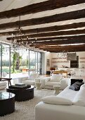 Large, open living room with curved metal wirechandeliers hanging from beamed ceiling made of unworked tree trunks