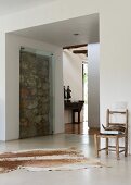 Zeitgenössische Architektur mit einem Mauerstück aus unbehauenen Natursteinen als Kunstwerk hinter einer Glasscheibe
