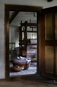 Blick durch offene Tür auf alten Webstuhl aus Holz, auf Boden Wäschekörbe