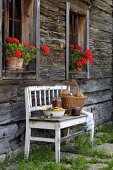 Fresh fruit in white metal bowl and basket on bench against facade of farmhouse
