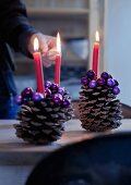 Large pine cones decorated with purple beads used as candlesticks