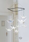 Wire mobile hung with origami cranes made from newspaper and writing paper