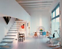 Open-plan living space with stairs and gallery and chairs in a mixture of styles