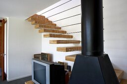 Daring staircase construction with treads projecting from wall and row of horizontal metal rods attached to stove pipe
