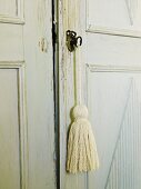 Türschlossdetail eines antiken Schrankes im Shabby Chic Stil mit einfacher Troddel am Schlüssel