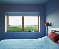 Schlichter Schlafraum in hellblau und Fenster mit Ausblick