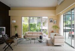 Living room with cream-coloured, Bauhaus-style sofas in front of large sliding windows