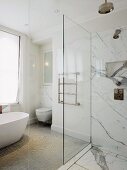 Free-standing bathtub, towel rail and floor-level shower with dramatic marble cladding