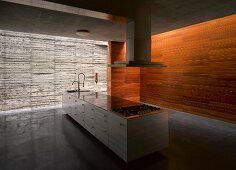 Plain kitchen island in large room with concrete & wood walls