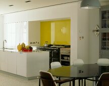 Open-plan kitchen with yellow glass wall & dining area