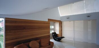 Wohnraum mit geschwungenen Wänden, Holzverkleidung, Sofa & Liegesessel