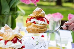 A profiterole filled with strawberries and cream on a cake slice