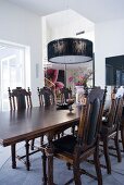 Elegant dining table and chairs in antique English style below modern pendant lamp
