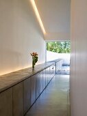 Minimalistischer Wohnraum mit modernem Sideboard unter indirekter Beleuchtung