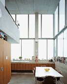 Dining area in kitchen with counter in front of high windows in contemporary house