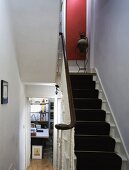 Schwarzer Teppichläufer auf weisser Holztreppe im modernisierten Wohnhaus
