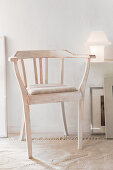 Rustikaler Stuhl mit weiss geölter Oberfläche vor Wand