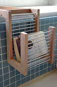 Rack made of wood and metal rods on blue-tiled bathtub