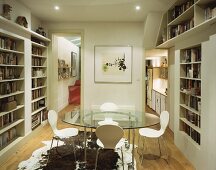 Zimmer mit rundem Glastisch und eingebauten Bücherregalen