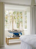 Imposantes Modell-Segelboot im Fenstererker eines weissen Schlafzimmers