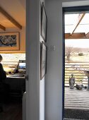 Blick auf karge Landschaft - Holzterrasse mit Skulpturen und schmales, liegendes Fenster in Homeoffice