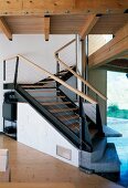 Gewendelte Holz/Stahltreppe mit schrägen Elementen und Antrittsstufen aus Stein in zeitgenössischem Tiroler Holzhaus