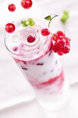 Redcurrants falling into a layered yogurt dessert