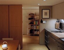 A modern living room-cum-kitchen with a view of a neighbouring room and a bookshelf